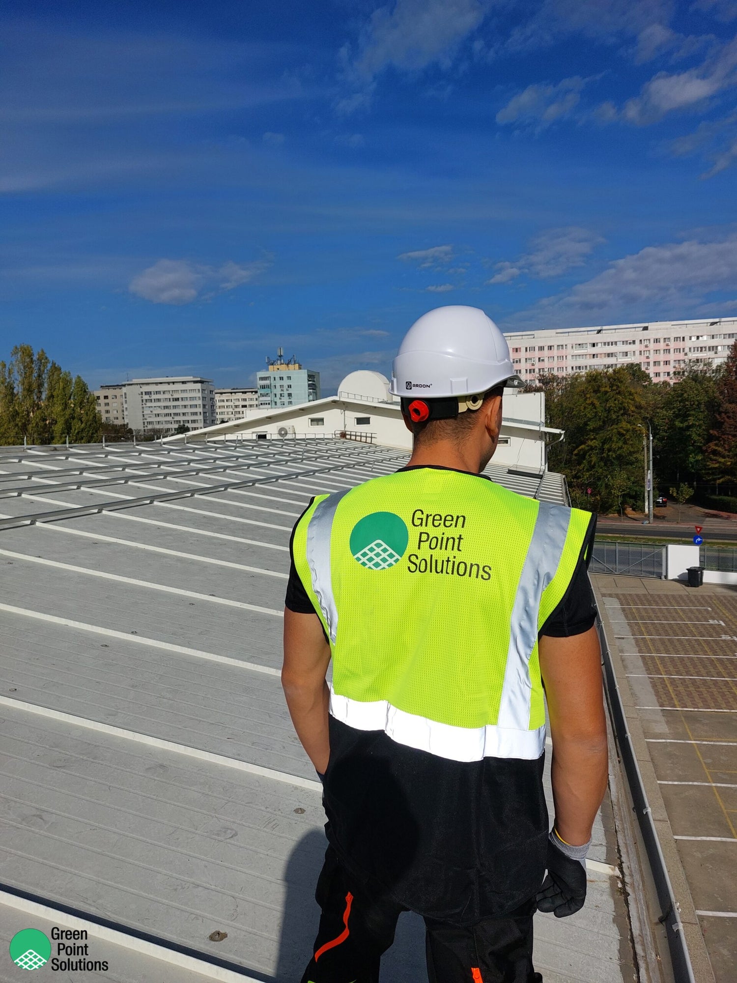 Person wearing a high-visibility vest with 'Green Point Solutions' on a rooftop.